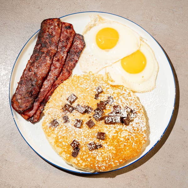 Bite Food & Coffee Co breakfast plate with pancakes, bacon, and two fried eggs.