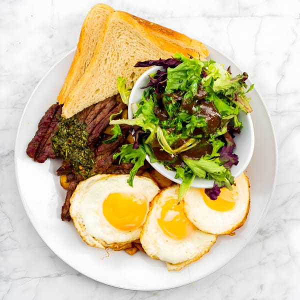 Bite Food & Coffee Co's breakfast plate with steak, fried eggs, toast, and a side salad.